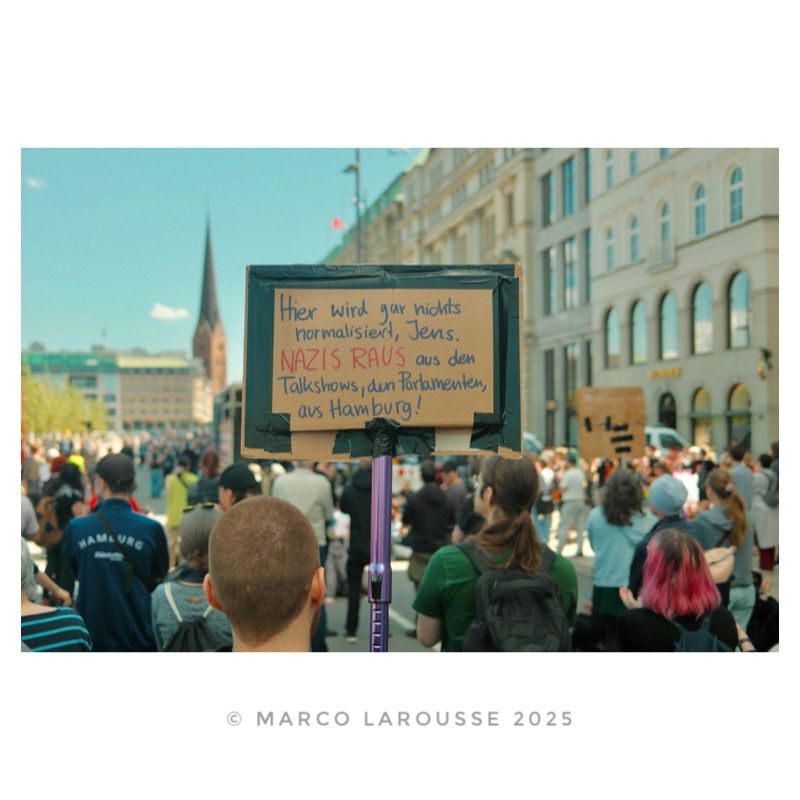 Ein Demonstrant hält ein Schild mit dem Text: „Hier wird nicht bormalisiert, Jens. Nazis Raus aus den Talkshows, dem Parlament, aus Hamburg!“