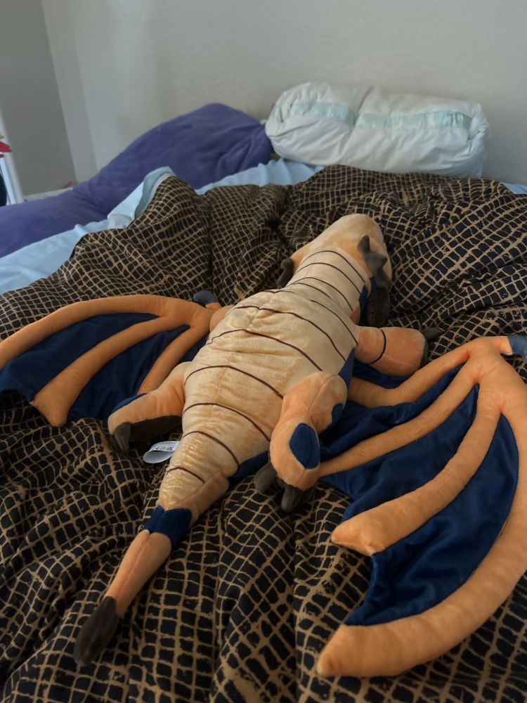 An orange and blue dragon plushie splayed out on it’s back