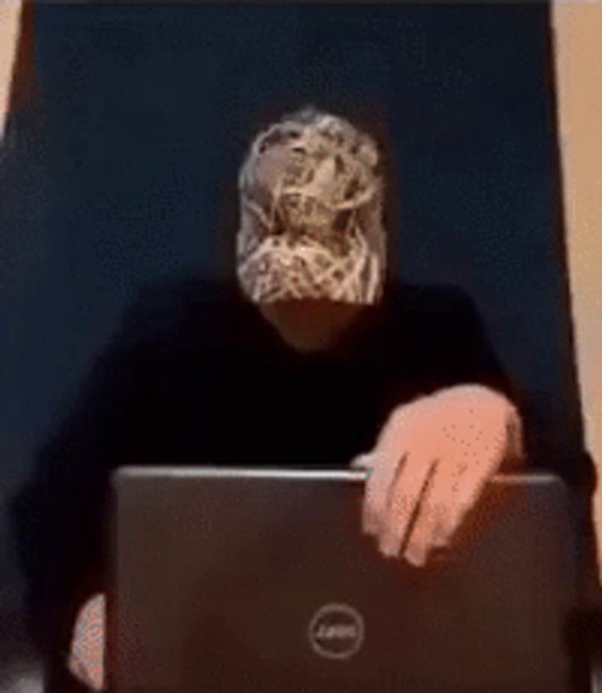 a man wearing a mask is typing on a dell laptop