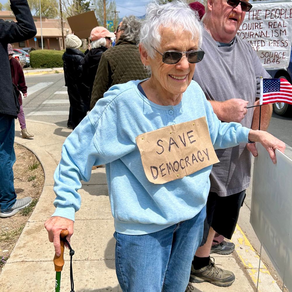 50501 Hands Off protest today in Taos, New Mexico, senior protestor with a sign pinned to shirt “Save Democracy”
