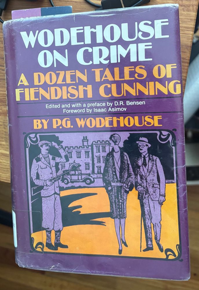 A hardcover book. The background is purple. In bold white letters it says "Wodehouse on crime" and underneath in orange letters "A dozen tales of fiendish cunning. By P.G. Wodehouse." Below the text there is an illustration depicting an English mansion, a car, and three people: two men and a woman, all dressed in the fashionable styles of the interwar era.