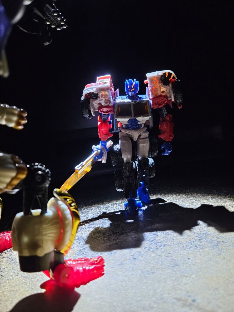 Laser Optimus Prime with his sword out, looking at RID Galvatron in the foreground
