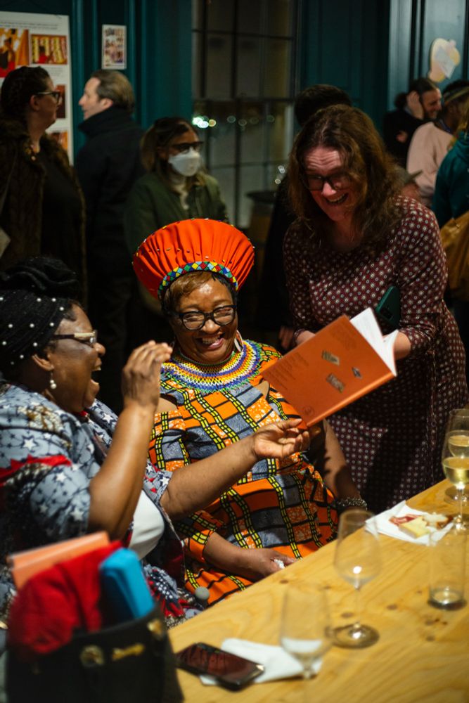Three people smiling as they look through the comic book anthology