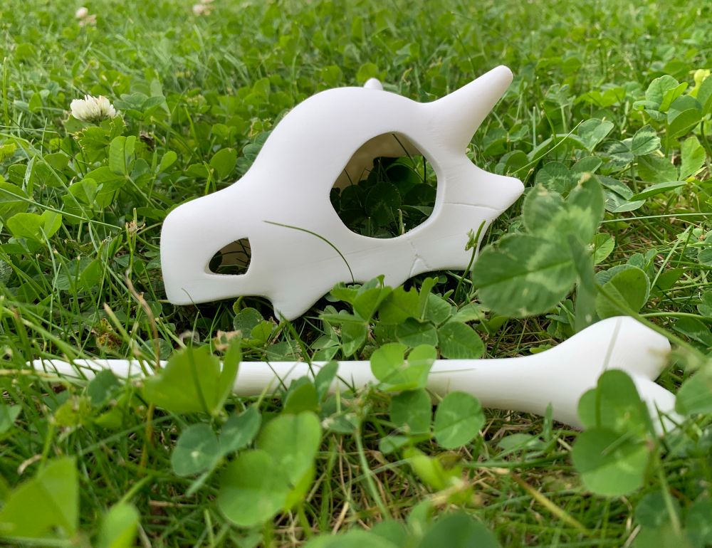 3d printed Cubone skulls outside on the grass and clover . 