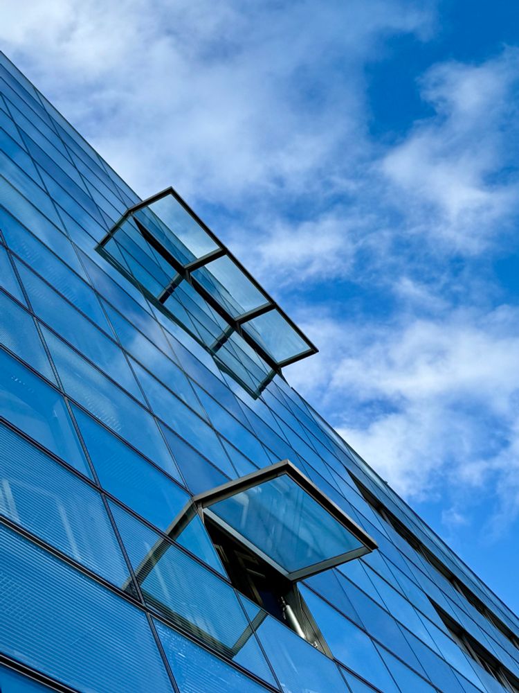 An einer strukturierten Glasfassade sind 2 Fensterluken aufgestellt