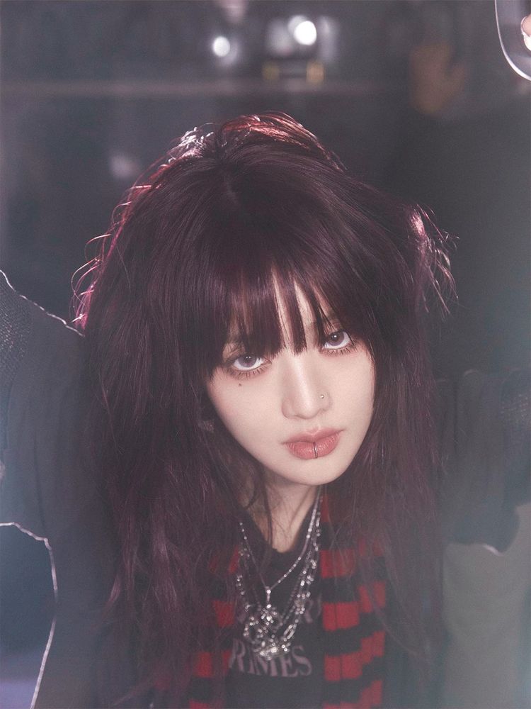 A close-up photo of Minnie. She has dark red hair and is wearing a black T-shirt and a red and black striped scarf