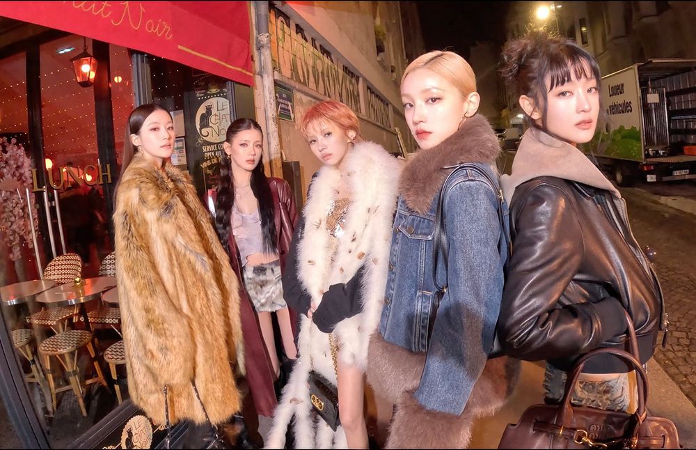Shuhua, Miyeon, Soyeon, Yuqi and Minnie (i-dle members) are on the street at night, in front of a cafe/restaurant