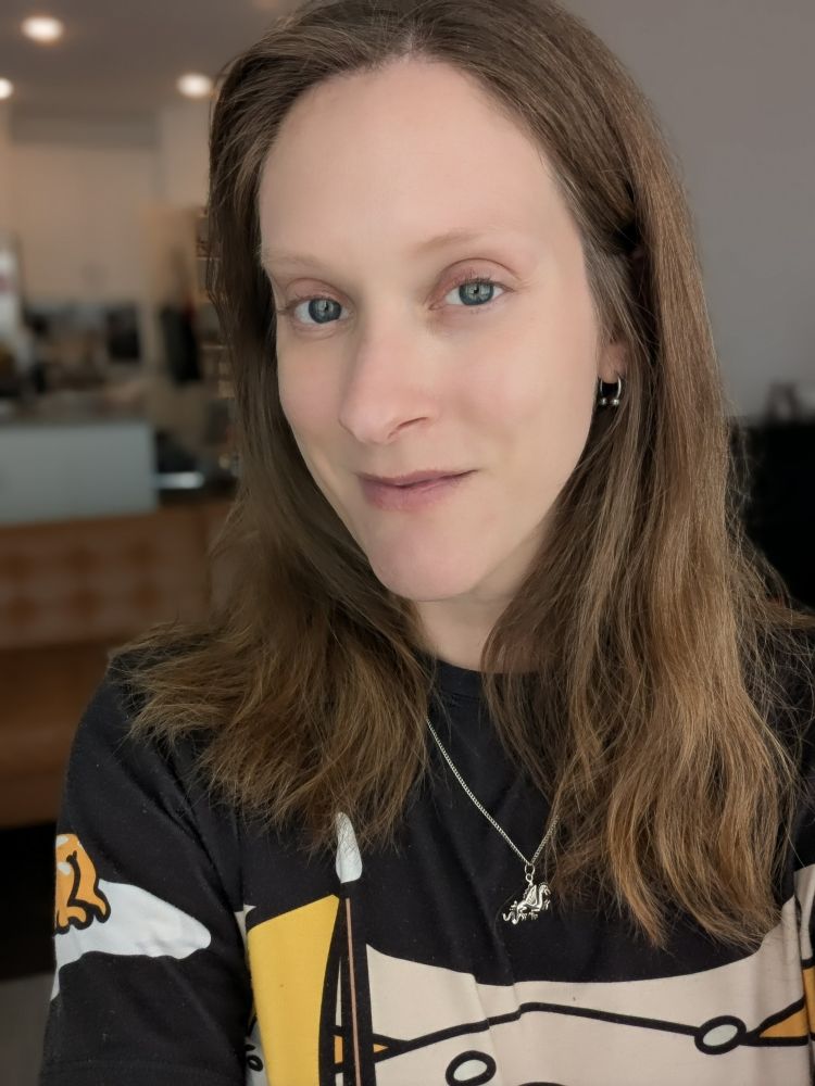 Karin looking at the camera with minimal makeup on and a gentle smile, wearing a gudatama shirt