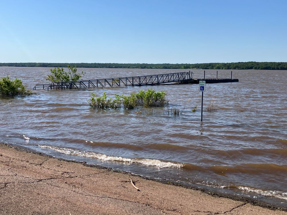 Photo of shoreline of Lake Thunderbird in Norman, Oklahoma. A large portion of the dock is underwater and the disabled parking spot is now ten feet from the shoreline.