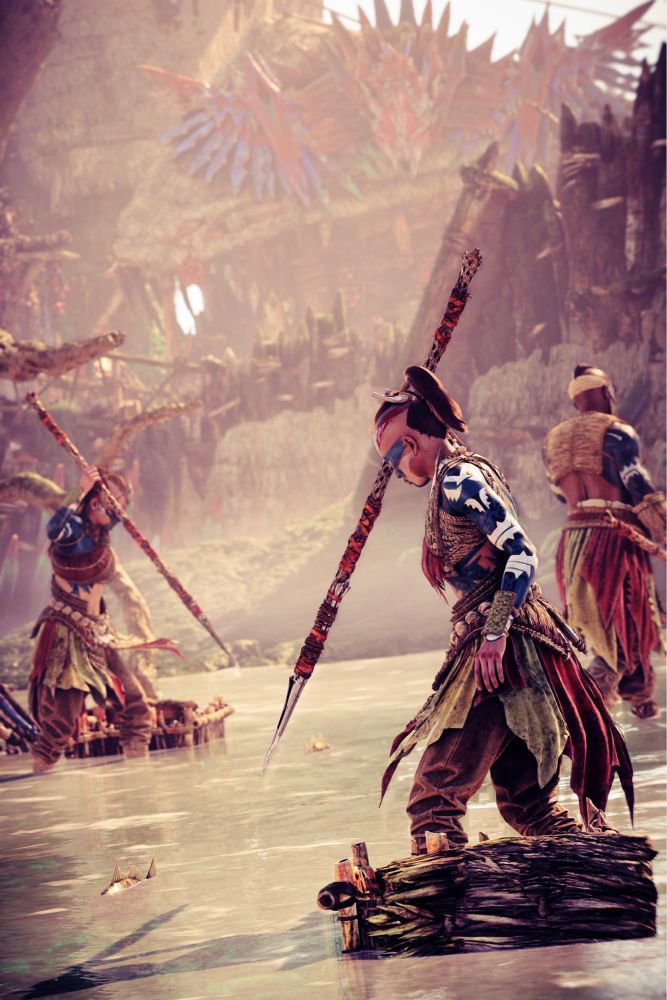 A virtual photograph from Horizon Forbidden West featuring some of the Lowland Tenakth just outside of the Fall’s Edge settlement. Two of them are spear fishing and have their spears up and ready to strike, forming a V shape within the picture. A third is walking away, possibly towards another fishing spot or back into the settlement.