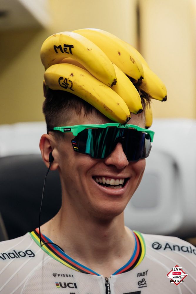 Young Slovenian champion cyclist Tadej Pogačar (Team Emirates XRG) wears a bunch of yellow bananas, in jest, as bike helmet 