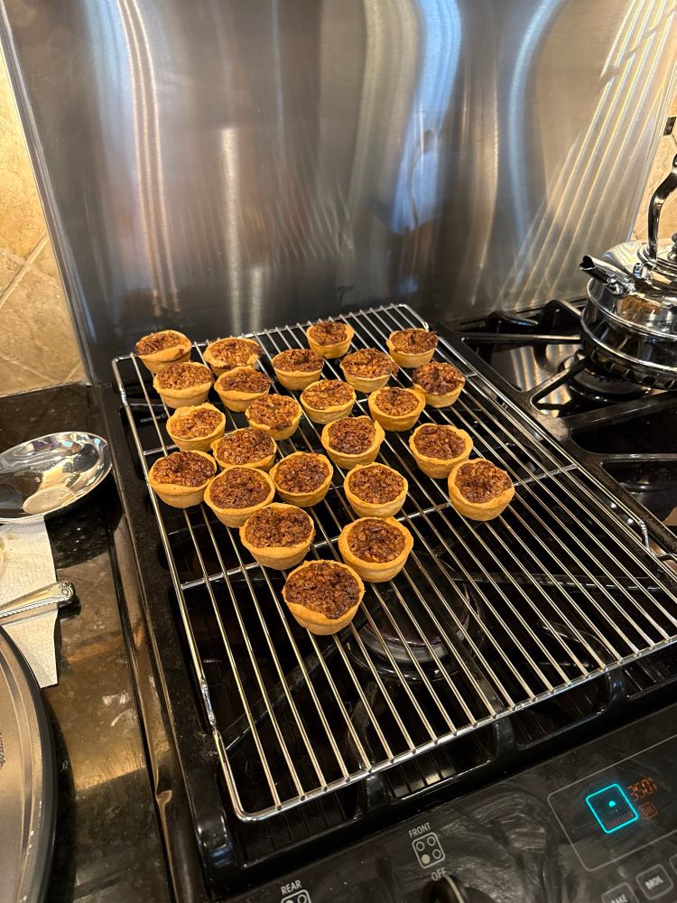 Miniature pecan pies cooking on a wire rack