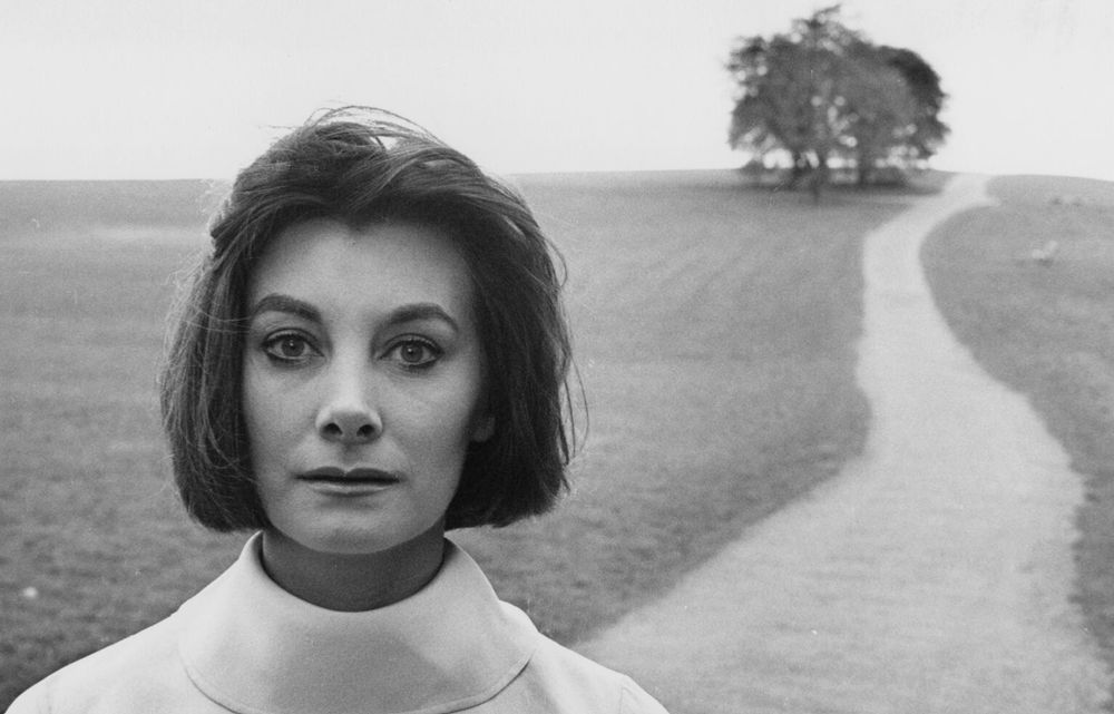 the actor Jean Marsh, who has recently died, stands on a county lane in a 1961 portrait by photographer Brian Shuel