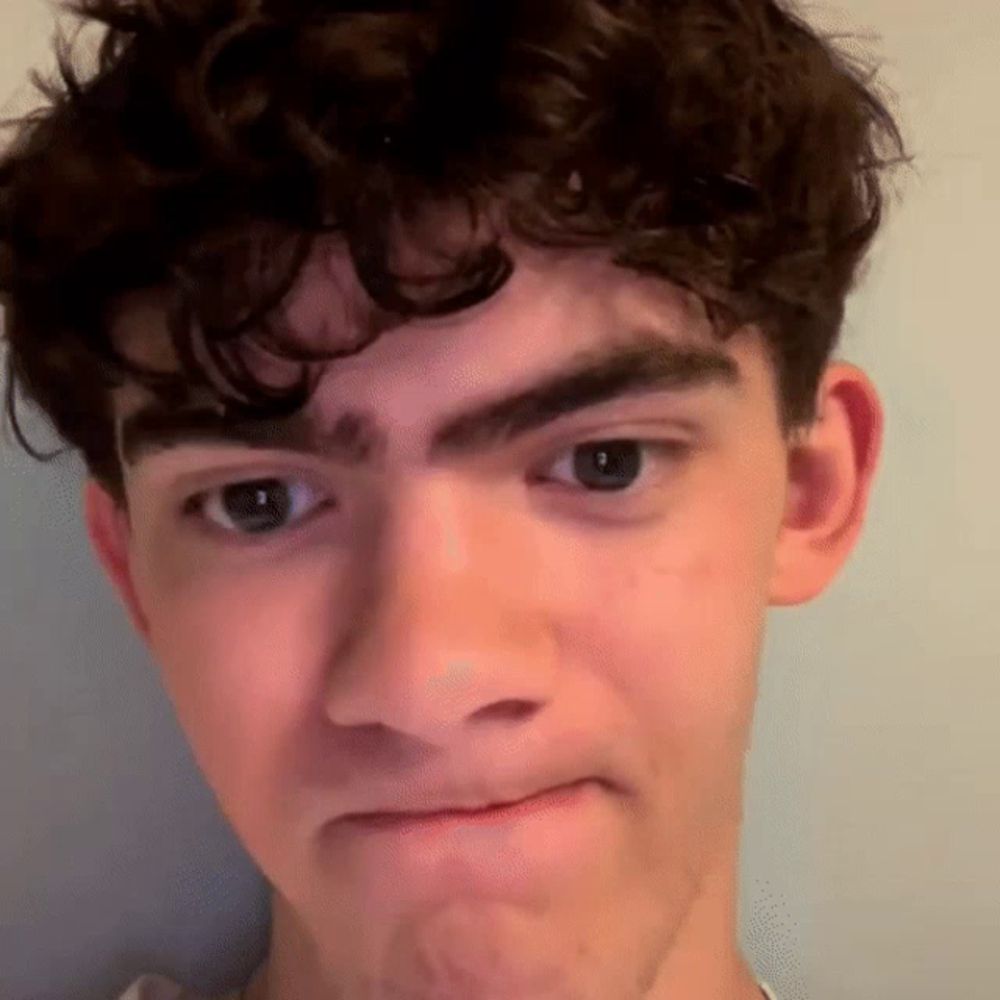 a young man with curly hair making a face