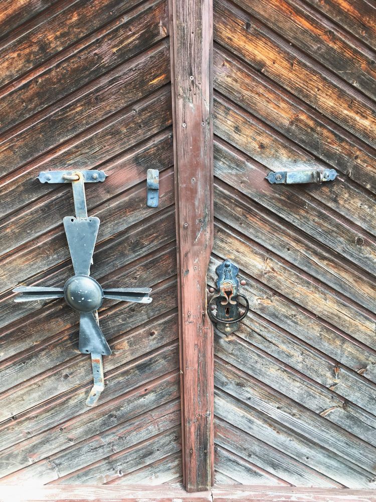 Foto zeigt eine braune Holztüre mit Metallgriff und - Riegel