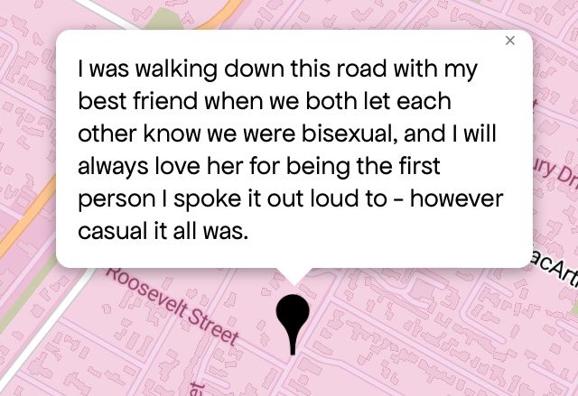 Queering The Map 
Image shows a pink map with a black pin drop on location with message that reads “I was walking down this road with my best friend when we both let each other know we were bisexual, and I will always love her for being the first person I spoke it out loud to - however casual it all was.”