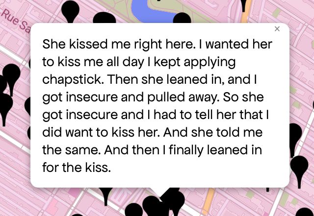 Queering The Map 
Image shows a pink map with a black pin drop on location with message 

“She kissed me right here. I wanted her to kiss me all day I kept applying chapstick. Then she leaned in, and I got insecure and pulled away. So she got insecure and I had to tell her that I did want to kiss her. And she told me the same. And then I finally leaned in for the kiss”