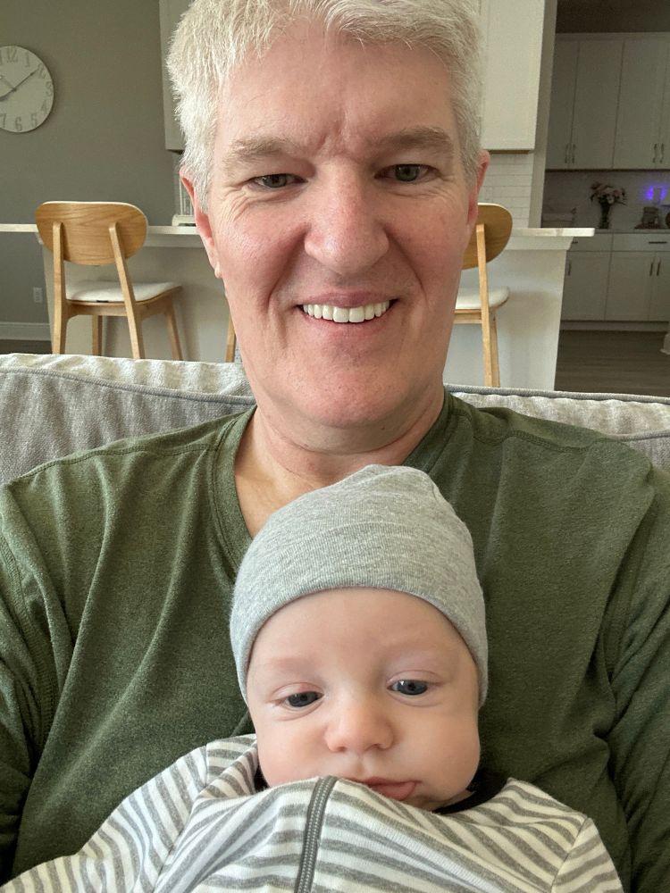 A man holding a young baby and smiling 
