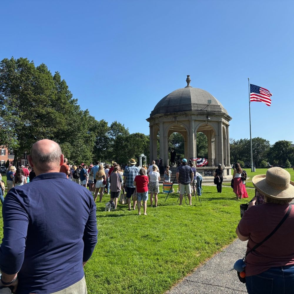 Salem Common Bandstand with a crowd gathered and the American flag flying in the background.