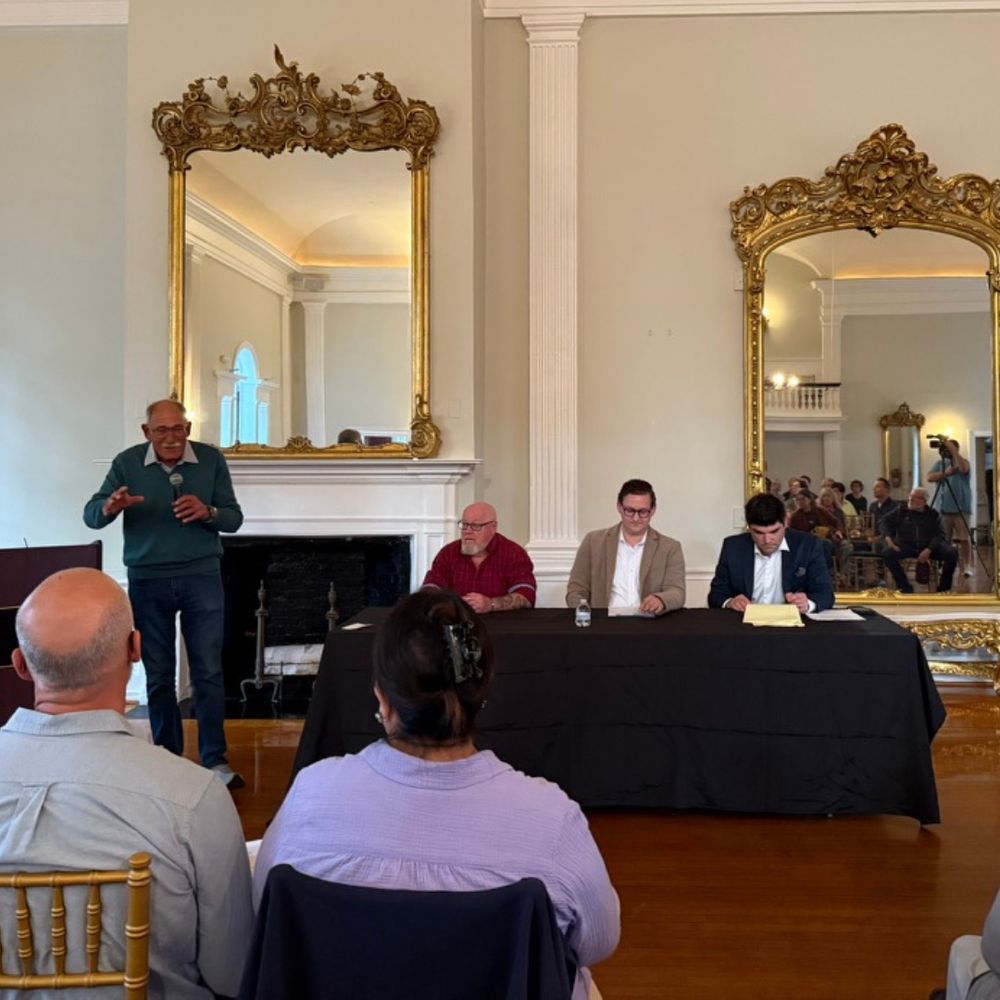 Candidates sit at a table while being introduced.