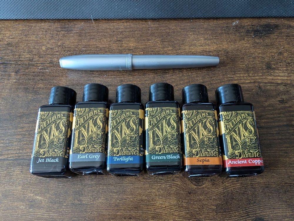 a row of fountain pen ink bottles of varying colours and a silver Sheaffer...