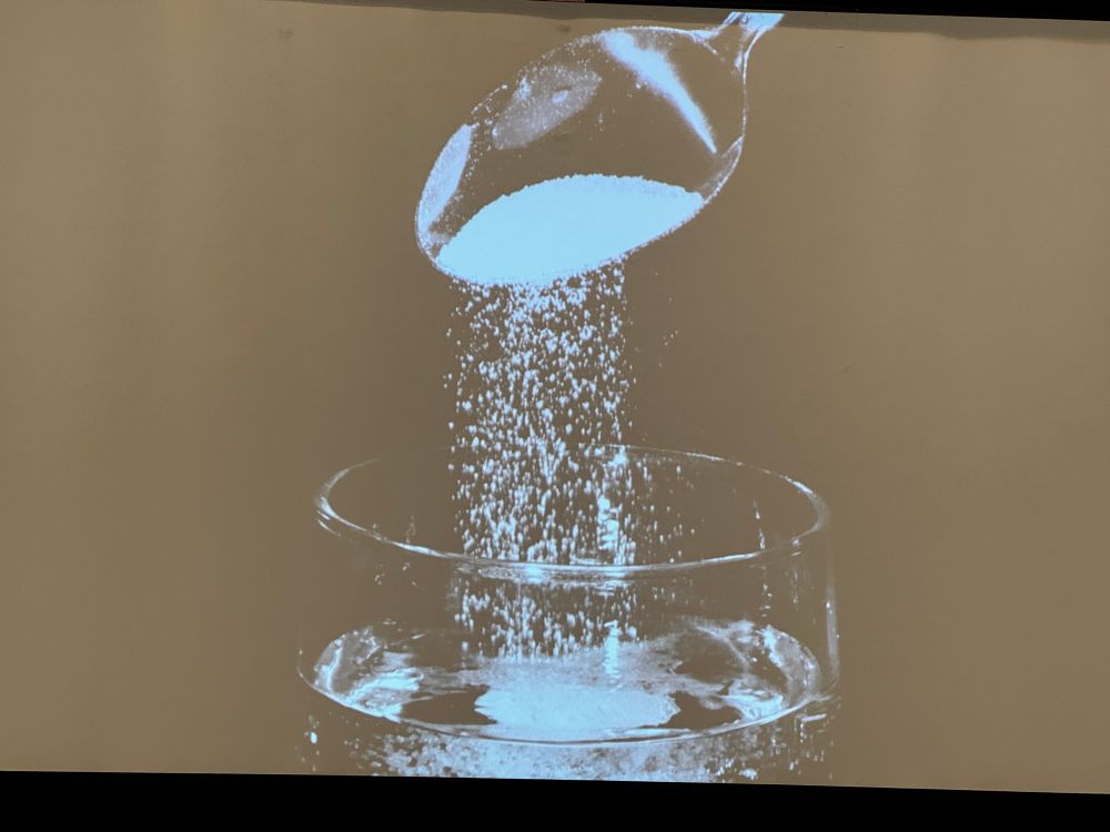 An image of a spoon of salt spilling into a glass of water