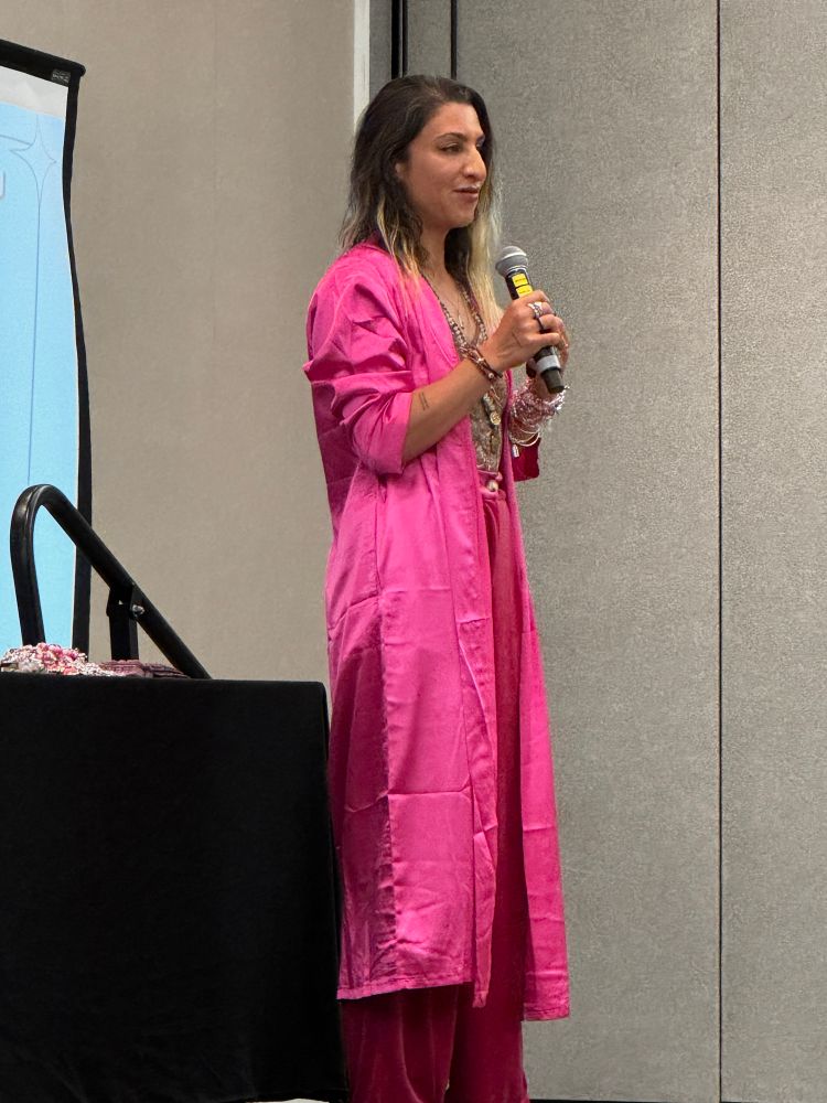 Vanessa on stage presenting- in a shiny pink robe