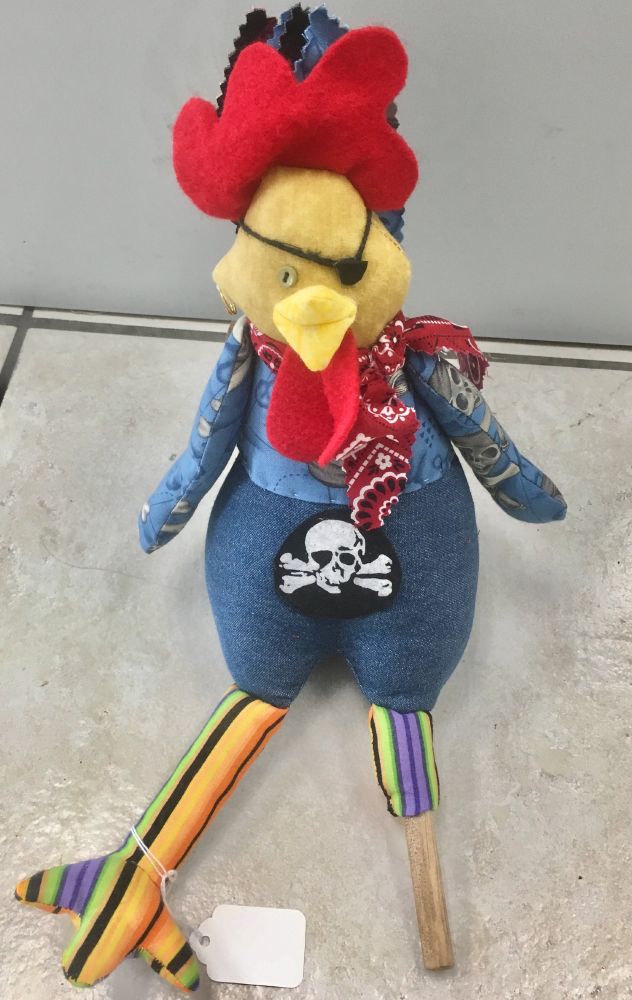 
The gifted artist Joan Walters has skillfully encapsulated the mesmerizing essence of Key West and the Florida Keys in her stunning work, "Fabric Art / keys style / rooster" This is a handmade plush toy in the shape of a rooster. The rooster is dressed as a pirate! It has a red felt comb, a black eyepatch, a red bandana, and a blue denim jacket with a skull and crossbones patch. The rooster's legs are made of striped fabric and are attached to wooden dowels. The toy is sitting on a tiled floor.  The toy is a unique and fun piece of art. The handmade details and the colorful fabric make it a fun and whimsical toy. It would be a great gift for a child who loves pirates or roosters. The toy is also a great conversation starter and would be a great addition to any home decor.  This is a one-of-a-kind piece of art that would be sure to be treasured for years to come. 