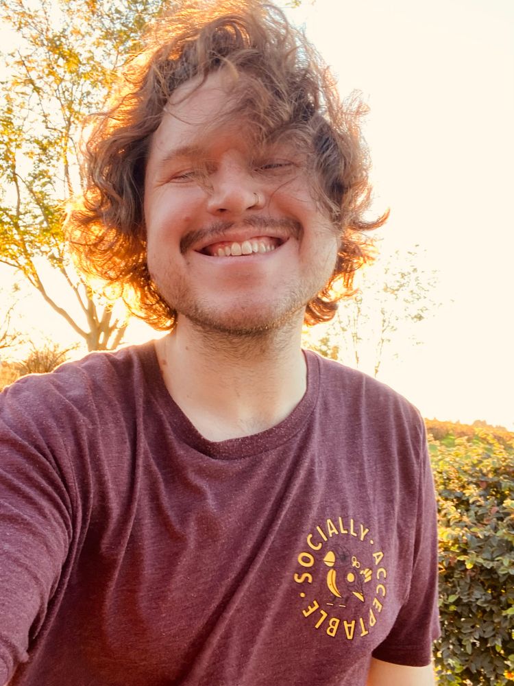 tuck selfie she is smiling and wearing a maroon t shirt
