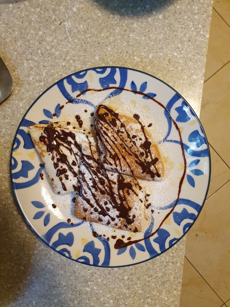 Naleśniki z twarogiem, polane sosem czekoladowym i posypane cukrem pudrem