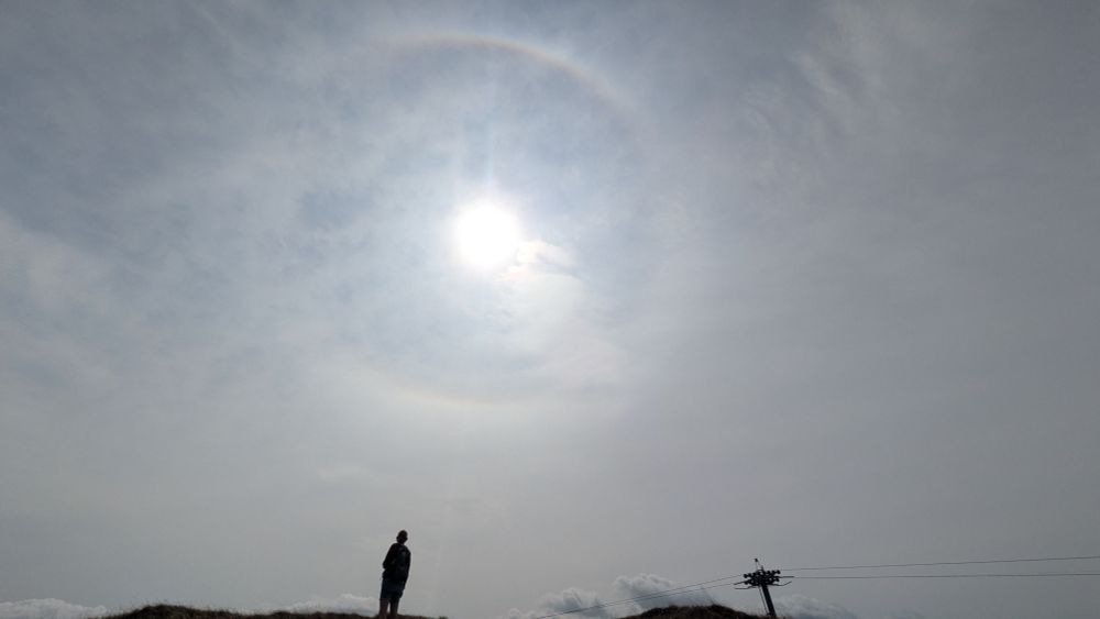 Silhouette of a person below a sun halo.