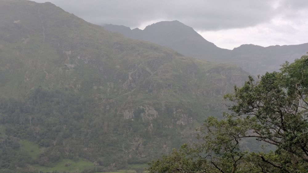 View of distant mountain peaks in rain and dark clouds.
