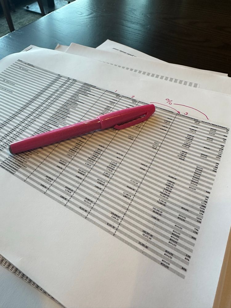 Printed spreadsheet with a pink pen on top 