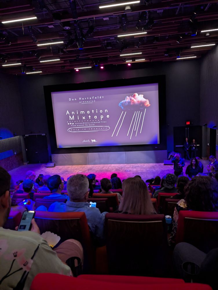 Movie theater dimly lit with neon purple and pink lighting. On the screen is the Animation Mixtape logo - a 3D cloud with 2D rain