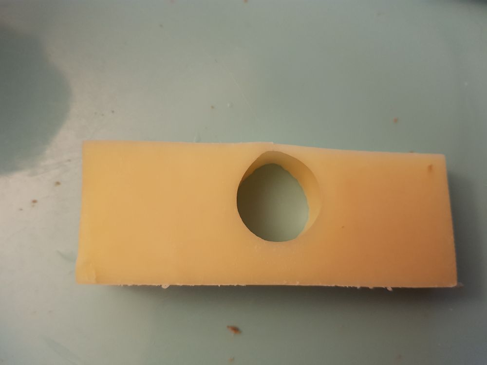 Ein rechteckiges Stück Edamer-Käse mit einem einzelnen Loch in der Mitte.