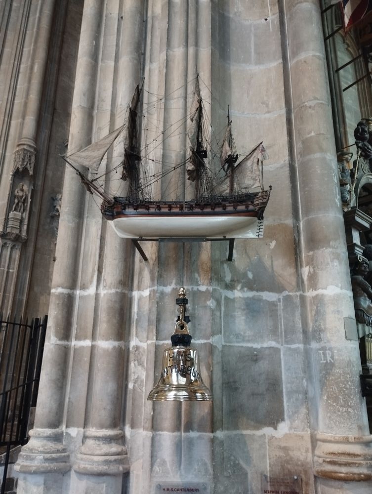 Ship's bell from the HMS Canterbury hanging below a replica of a different ship 