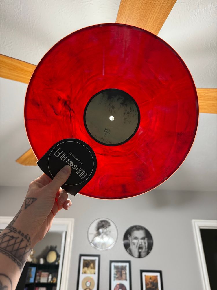 A vinyl record held up to the light to reveal a marbled blood red vinyl pressing. 