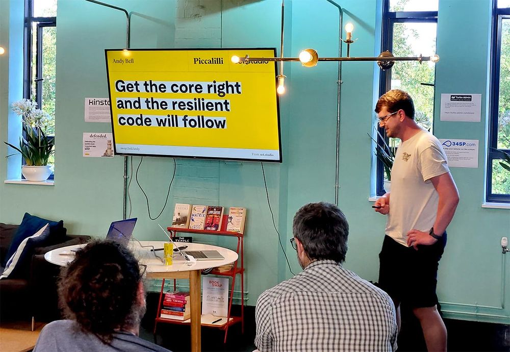 Andy beginning his talk with the title on the screen with a yellow background, black text and white highlight