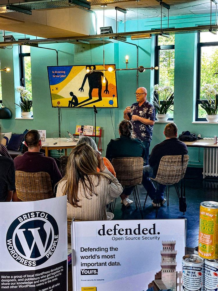 Elliott delivering his talk with signs in the foreground showing the BWP logo and Defended.net details