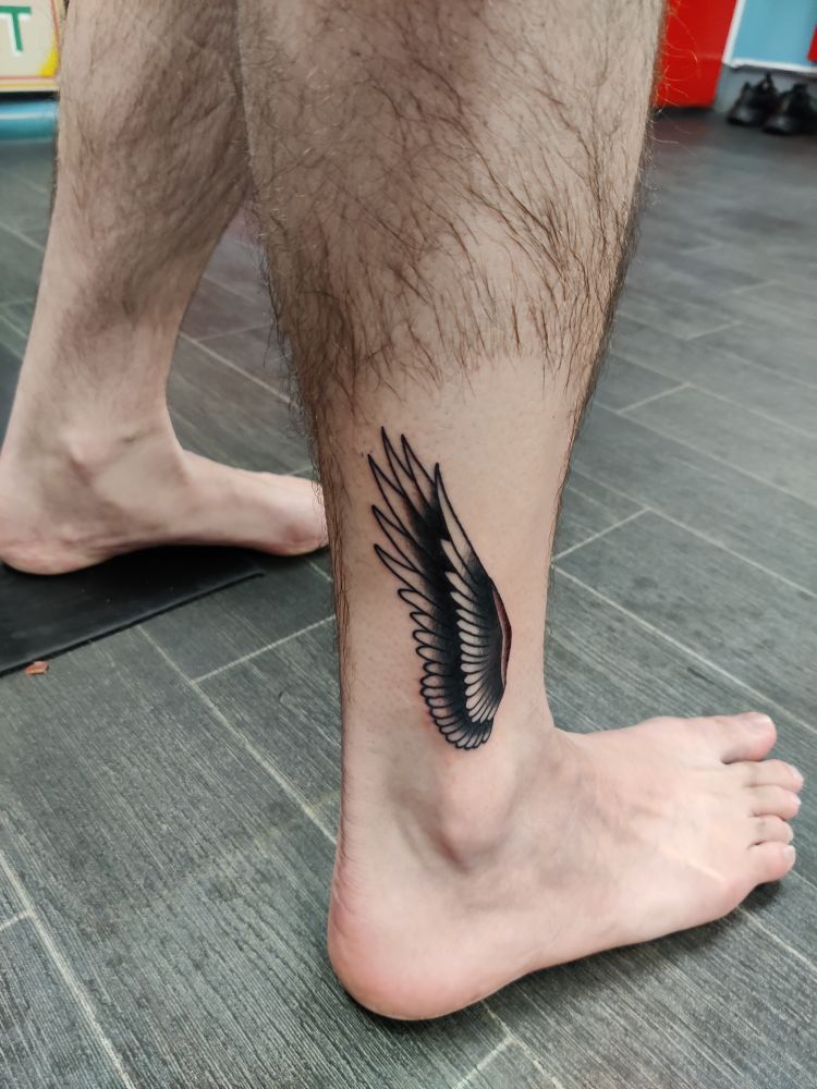 A monochrome tattoo of a bird's wing pointing upwards from my right ankle 