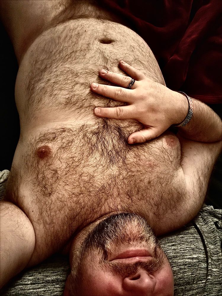  Naked hairy chested, bearded man with his right hand between his chest and tummy.