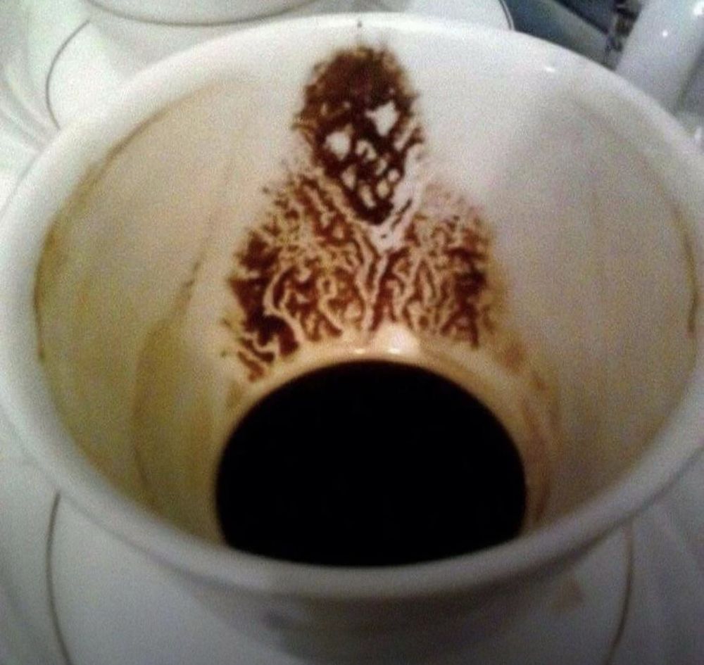 The photo shows a pattern of coffee grounds at the bottom of a cup that resembles a skull or another kind of monster.