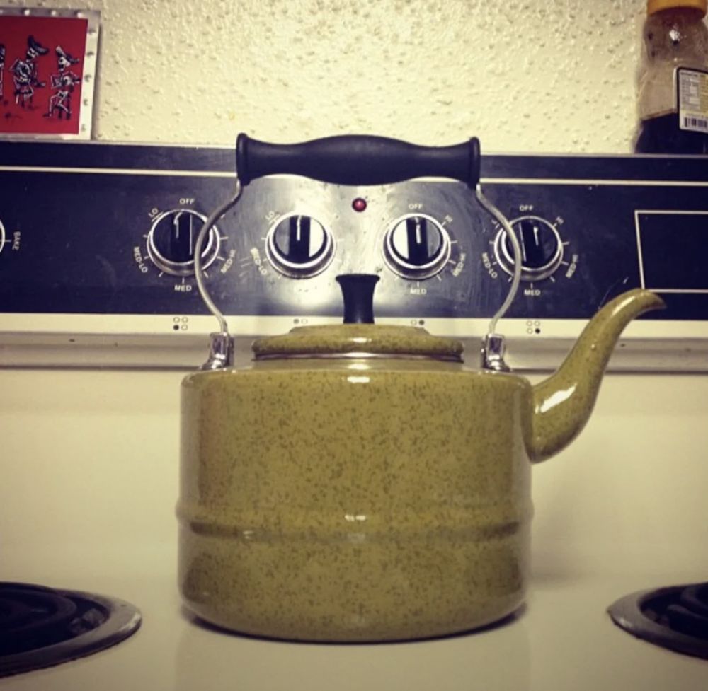 A kettle on a stove that looks like a cat.