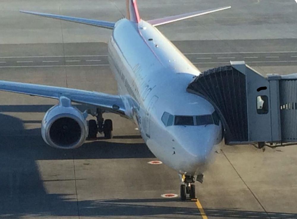 Plane with a bridge attached to its front door.