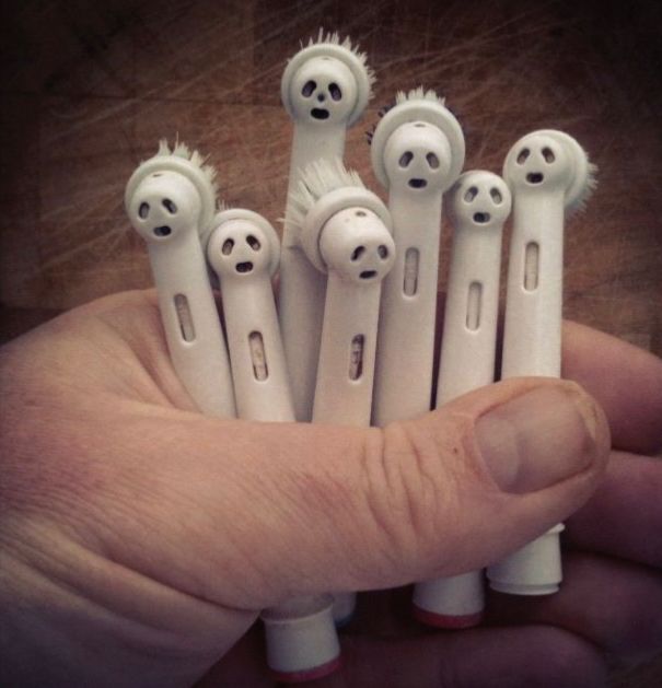Une main (aux ongles pas très propres 🫣) tient plusieurs têtes de brosse à dents électrique qui ressemblent à autant de monstres fantomatiques.
