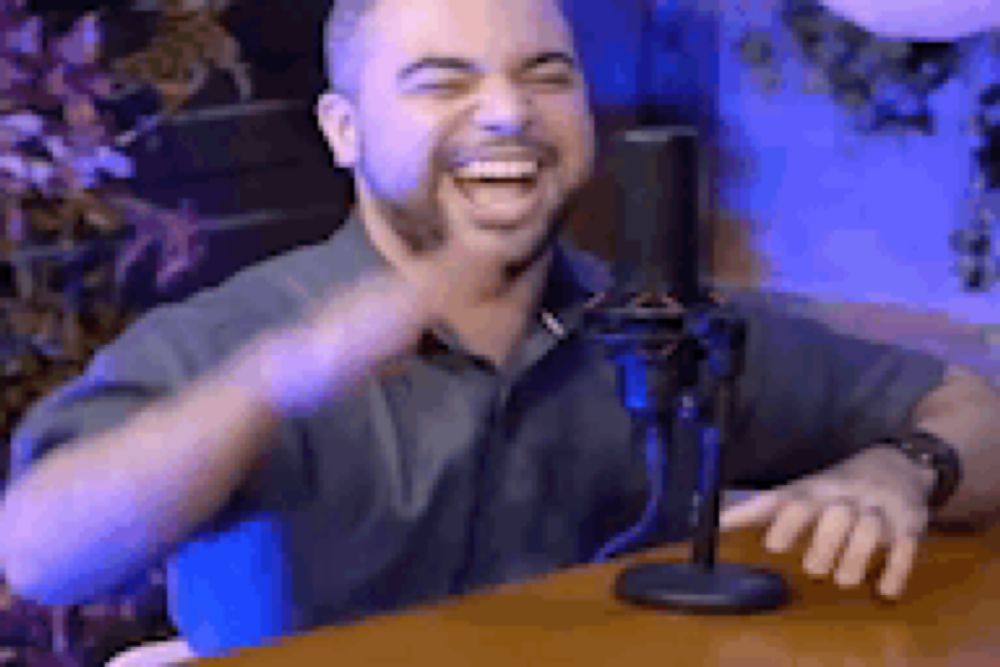 a man is laughing in front of a microphone .