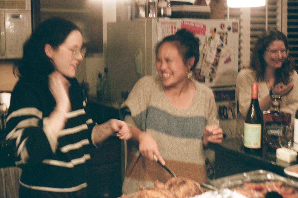 the same three people as the previous picture; jess has taken over carving the chicken and everyone is laughing