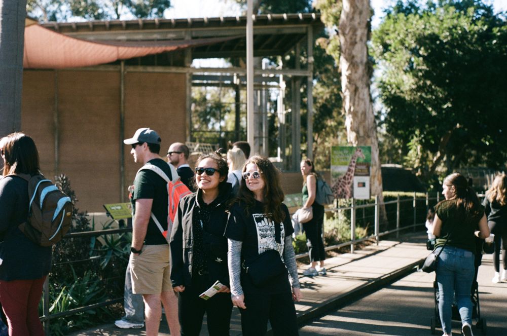 candid of jess and i smiling at someone offscreen on a sidewalk at the zoo