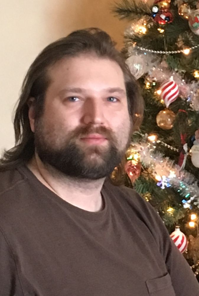 2 years pre-HRT. Scruffy and grungy with a dysphoria beard and a dead-inside expression even though it's clearly Christmas. Looks like wish.com Kenny Rodgers just did a double shift at a construction site with a hangover.