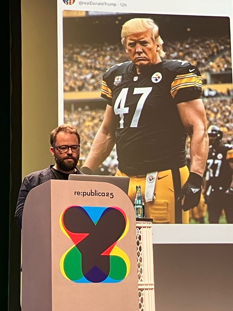 Roland Meyer auf der re:publica 2025 zu KI und digitalem Faschismus (mit KI-generierten Trump im Hintergrund).
